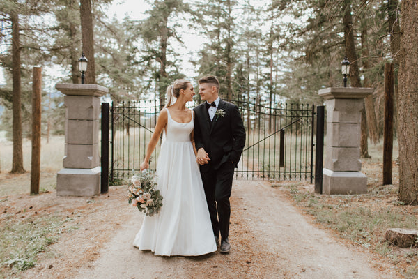 Married couple at a wedding venue in front of an iron gate in the forest